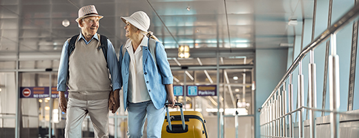 Image of senior couple pulling their suitcases at the airport